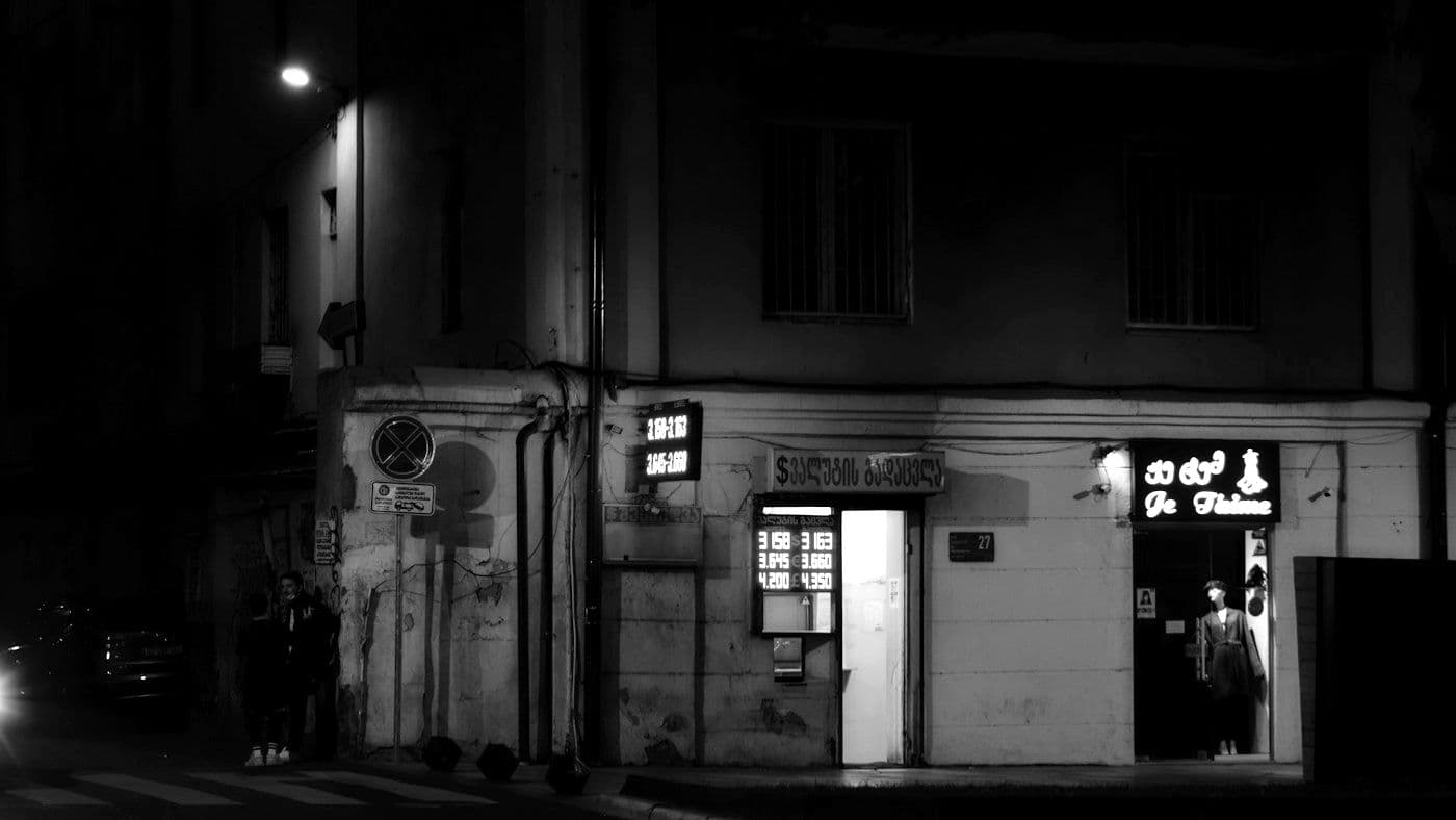 Lit shopfronts on a Tbilisi street at night